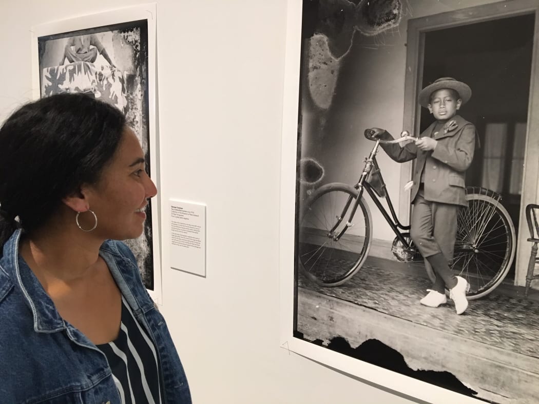 Photographer Edith Amituanai with an image of a Cook Islands boy taken by George Robson Crummer at their exhibition Edith and George: in our sea of Islands.
