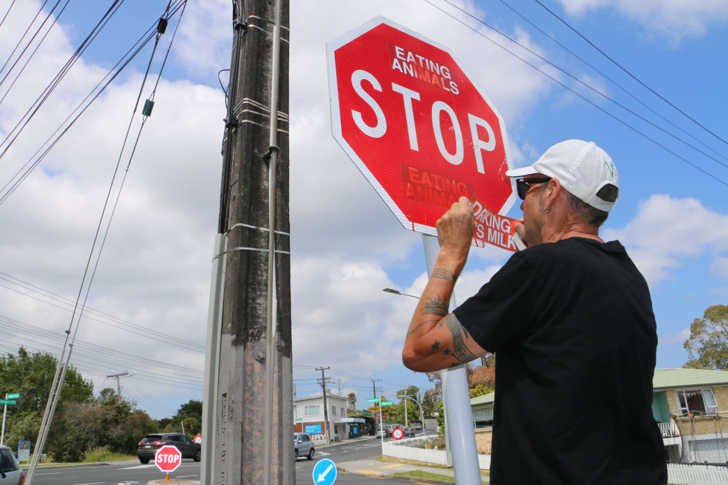 Vegan activist Deno Stock replaces an old sticker that's been painted over with a fresh one.