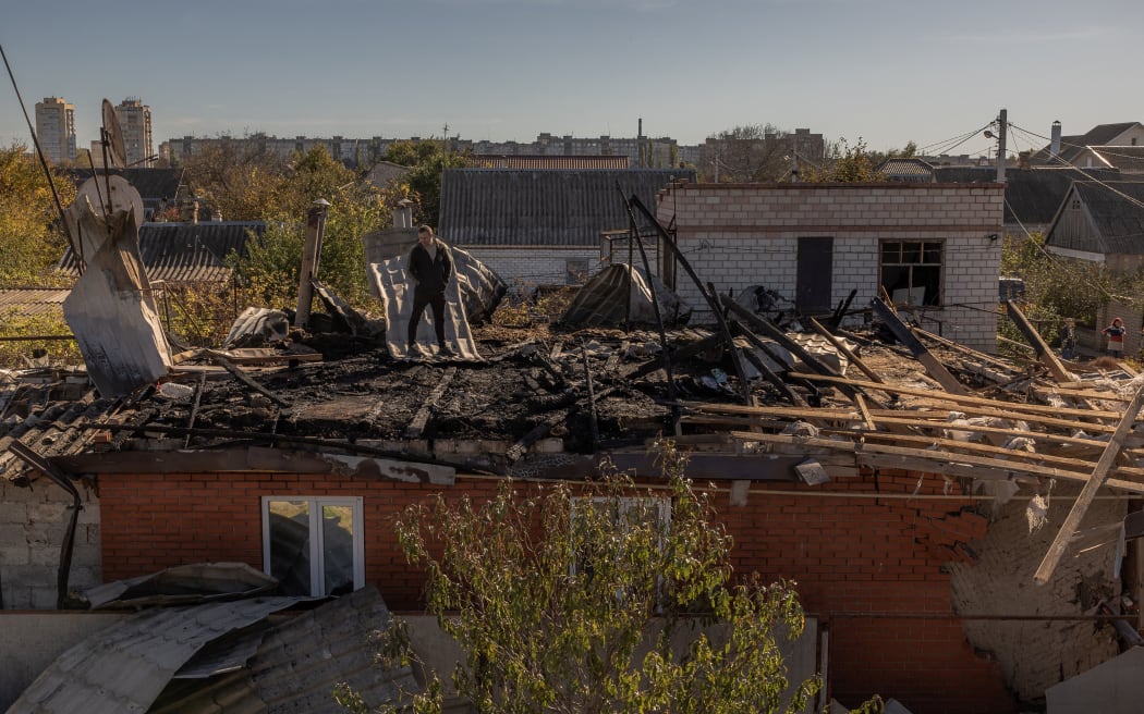 A man stands on a roof of a house that was damaged during an overnight Russian attack, in the southern city of Kherson, on October 30, 2023, amid the Russian invasion of Ukraine. (Photo by Roman PILIPEY / AFP)