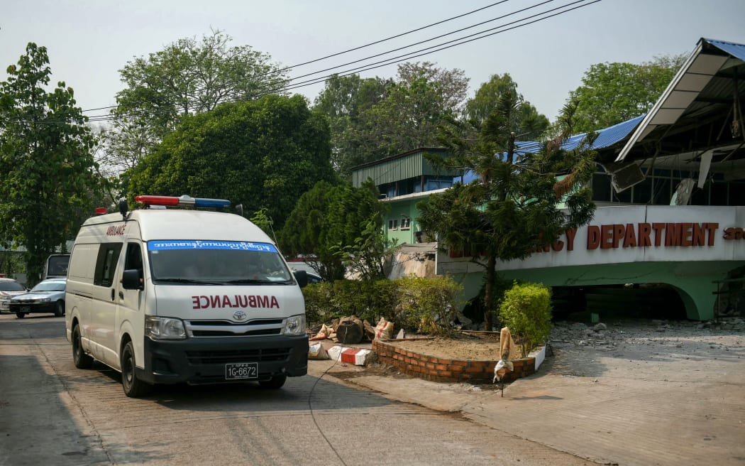 An ambulance is pictured next to a destroyed entrance area (R) of the emergency department of a hospital in Naypyidaw on 28 March 2025, after an earthquake in central Myanmar. A powerful earthquake rocked central Myanmar on March 28, buckling roads in capital Naypyidaw, damaging buildings and forcing people to flee into the streets in neighbouring Thailand. (Photo by Sai Aung MAIN / AFP)