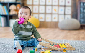 toddler with toy in mouth