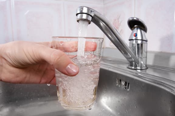 A glass is filled with drinking water from a tap