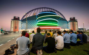 A group of men pray outside the Khalifa International Stadium, Doha, Qatar