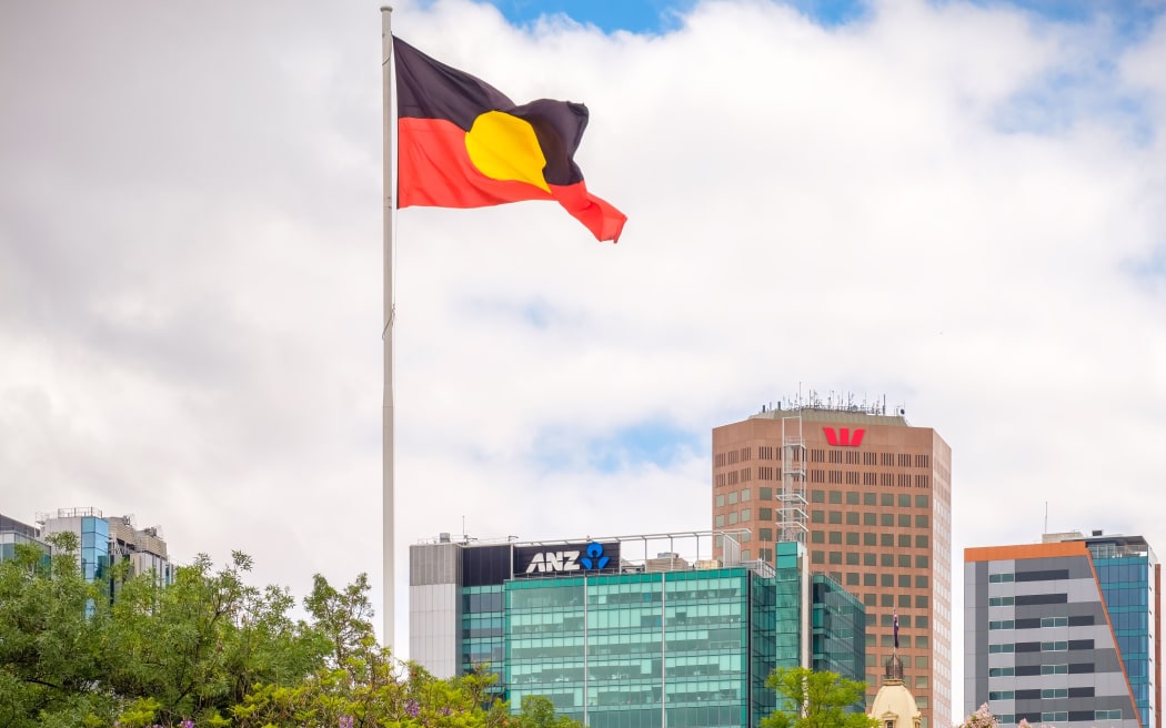Adelaide CBD, Australia - November 18, 2017: Australian Aboriginal flag waving above city skyline viewed from Victoria Square on a day