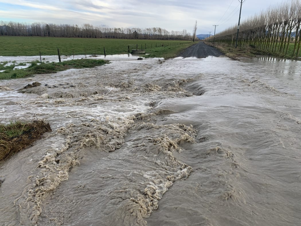 Water surges down Springfield Road via a breach of the north branch of the Ashburton River at the weekend.