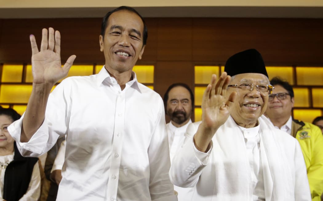 Indonesian President Joko Widodo, left, and his running mate Ma'ruf Amin wave after a press conference in Jakarta, Indonesia, on 17 April, 2019.