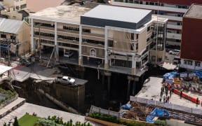 An overview shows a hole in the ground after a road collapsed near a hospital in Bangkok on September 24, 2025. (Photo by Chanakarn Laosarakham / AFP)