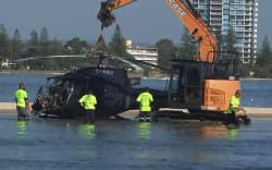 A day after the crash, airport workers prepare to remove a crashed helicopter that collided with another helicopter in Gold Coast on 2 January, 2023, killing four.