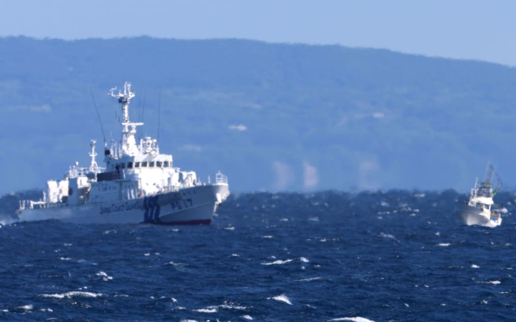 Japan Coast Guard vessel (L) and a fishing boat with U.S. Military personnel on board have conducted a search operation for missing U.S. Air Force members off Yakushima, Kagoshima Prefecture on December 2, 2023. The U.S. Air Force CV-22 Osprey transport aircraft, carrying eight crew members, crashed off the Yakushima Island on Nov. 29, killing at least one person and seven still missing. ( The Yomiuri Shimbun ) (Photo by Tosei Kisanuki / Yomiuri / The Yomiuri Shimbun via AFP)