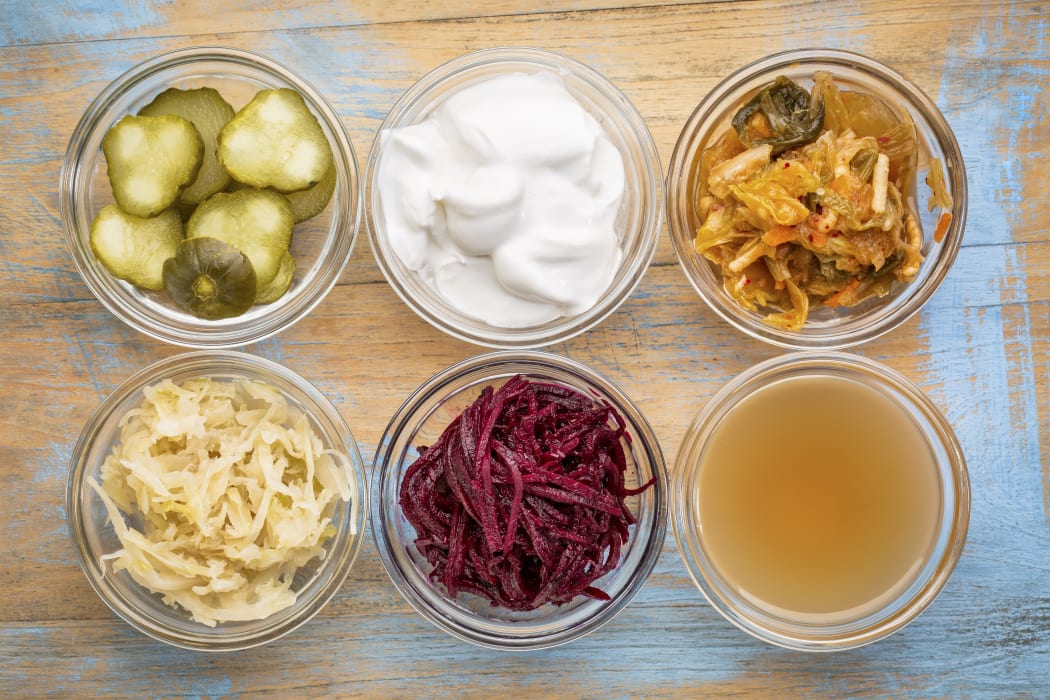 a set of fermented food great for gut health - top view of glass bowls against grunge wood:  cucumber pickles,  coconut milk yogurt, kimchi, sauerkraut, red beets, apple cider vinegar