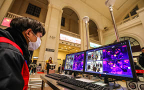 A railway staff member screens arriving passengers with thermal scanners at Hankou station in Wuhan.