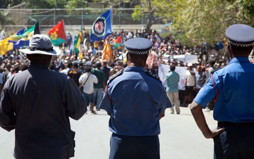 Papua New Guinea police officers watch on during a protest rally in 2013.