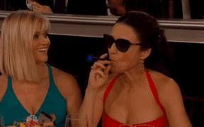 Julia Louis Dreyfuss smoking an e-cigarette at an awards ceremony.