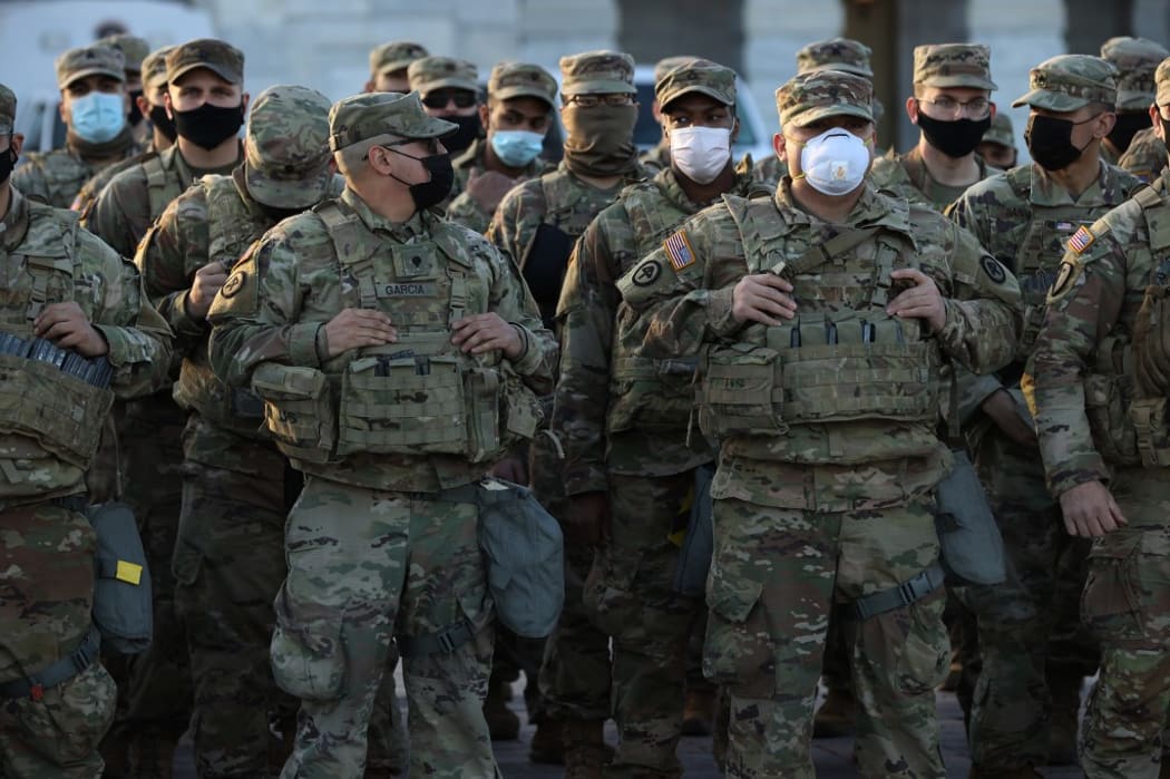 WASHINGTON, DC - JANUARY 14: National Guard troops pose for photographers on the East Front of the U.S. Capitol the day after the House of Representatives voted to impeach President Donald Trump for the second time January 14, 2021 in Washington, DC.