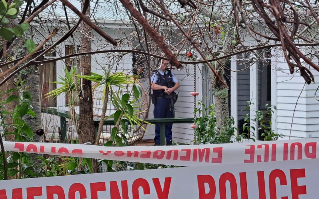 An armed police officer stands guard outside a house in Te Atatū Peninsula on 11 September, 2023.