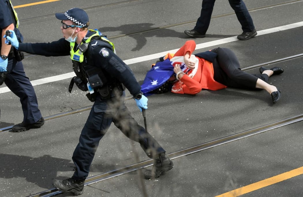 A protester is pushed to the ground by the police during an anti-lockdown rally in Melbourne on September 18, 2021.