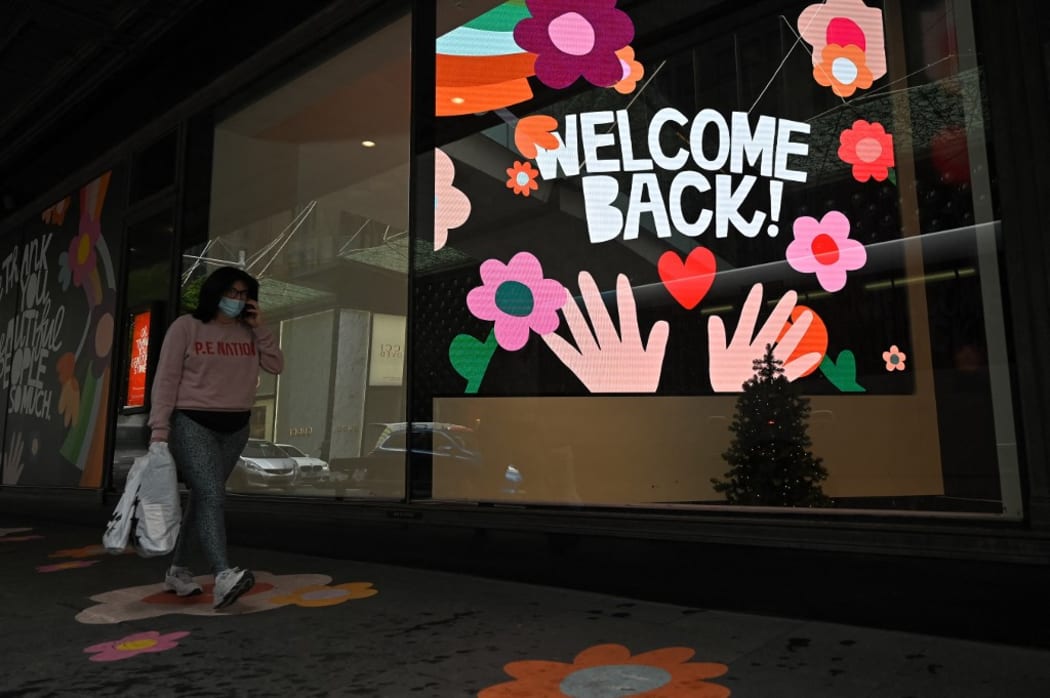 SYDNEY, AUSTRALIA - OCTOBER 12: A woman carrying a shopping bag walks past a ÃWelcome Back!Ã sign in the window of a retail store after stay-at-home orders were lifted across NSW, in Sydney, Australia, Tuesday, October 12, 2021.