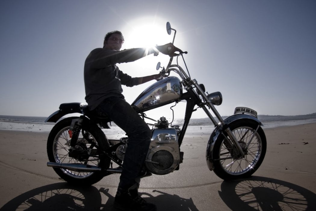 INDIA. MUMBAI CITY. BOMBAY. MOTORCYCLE AT BACK-LIGHTING ON THE BEACH OF BOMBAY