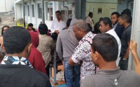 A group of people wait to hear about the detainees yesterday, as Attar Singh's lawyer Raman Singh ( white shirt )  receives a call.