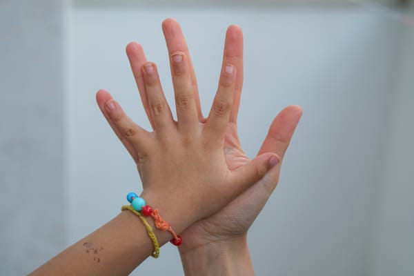 An adult hand rests against a child hand.