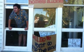 Scott Hita perches in the window of a house surrounded by placards