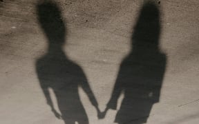 The shadows of two people hold hands.