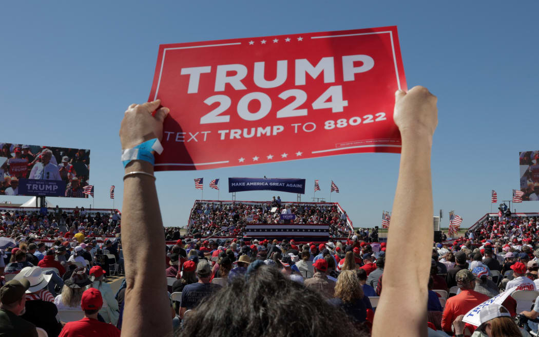 A supporter of former US President Donald Trump holds a "Trump 2024" sign at a 2024 election campaign rally in Waco, Texas, March 25, 2023. - Trump held the rally  at the site of the deadly 1993 standoff between an anti-government cult and federal agents. (Photo by Shelby Tauber / AFP)
