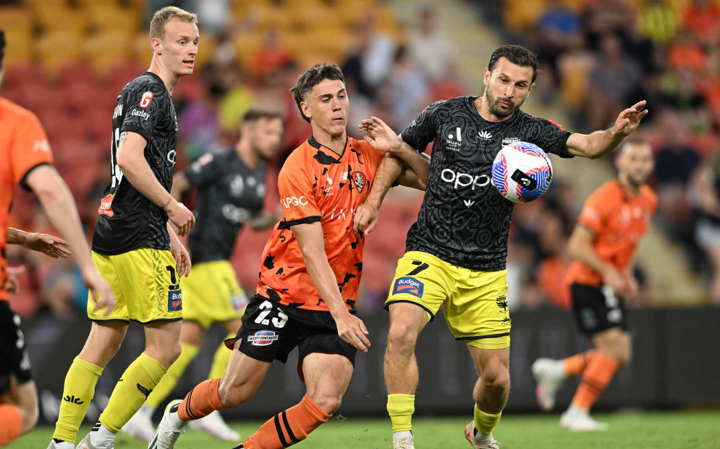 Keegan Jelacic (centre) of the Roar contests for the ball against Kosta Barbarouses (right)of the Phoenix during the A-League Men Round 15 match between Brisbane Roar and the Wellington Phoenix at Suncorp Stadium in Brisbane, Friday, February 2, 2024. (AAP Image/Darren England/ Photosport