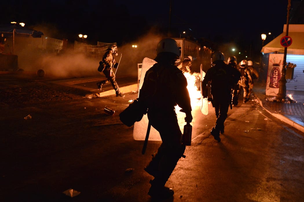 Riot policemen run after protesters throwing petrol bombs in central Athens.