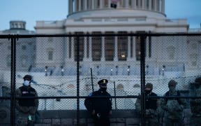 A Capitol Police officer stands with members of the National Guard behind a crowd control fence surrounding Capitol Hill a day after a pro-Trump mob broke into the US Capitol on January 7, 2021, in Washington, DC.