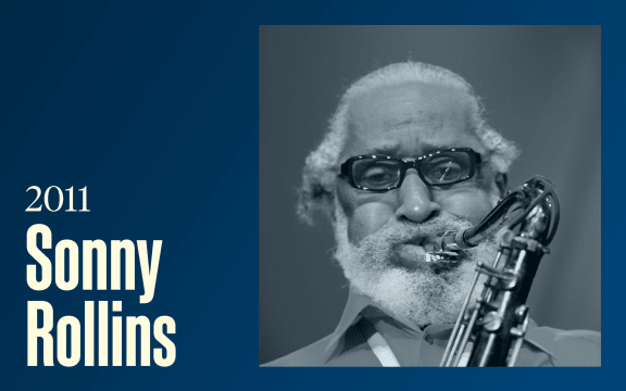 A grey bearded man plays the saxophone, text reads "2011, Sonny Rollins"