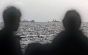 This handout photo taken on February 13, 2025 and released by The Australian Defence Force shows sailors onboard the Royal Australian Navy ship HMAS Arunta looking at the People's Liberation Army-Navy (PLA-N) Fuchi-class replenishment vessel and Weishanhu Jiangkai-class frigate Hengyang in the Tasman Sea. Australia's foreign minister voiced concern on February 21 over live fire drills conducted by three Chinese warships sailing off the country's east coast. (Photo by Handout / AUSTRALIAN DEFENCE FORCE / AFP) / RESTRICTED TO EDITORIAL USE - MANDATORY CREDIT "AFP PHOTO /  AUSTRALIAN DEFENCE FORCE" - NO MARKETING NO ADVERTISING CAMPAIGNS - DISTRIBUTED AS A SERVICE TO CLIENTS