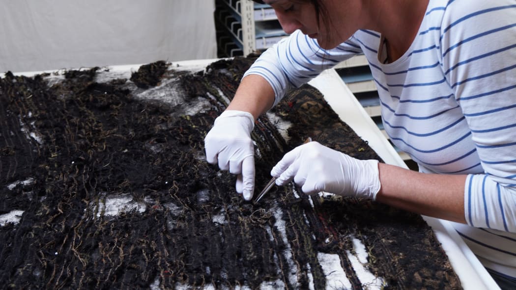Karin Konold carefully looking at the deterioration of black muka.