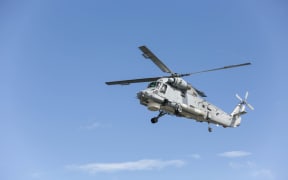 A helicopter lowers itself to land to collect luggage of evacuees heading to the HMNZS Canterbury.