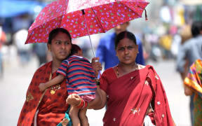 Two women and a child shelter under an umbrella in Hyderabad on Monday.
