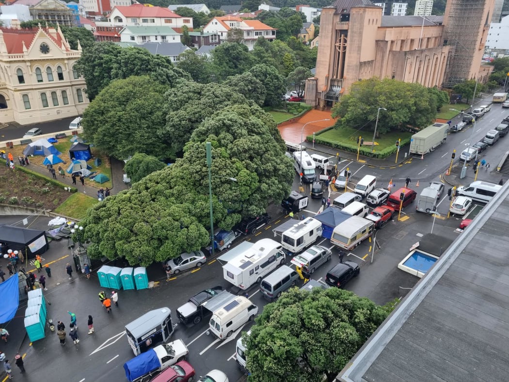Protesters' vans and cars blocking the corner of Molesworth St and Hill St outside Parliament grounds, and tarpaulin awnings set up on the footpath.