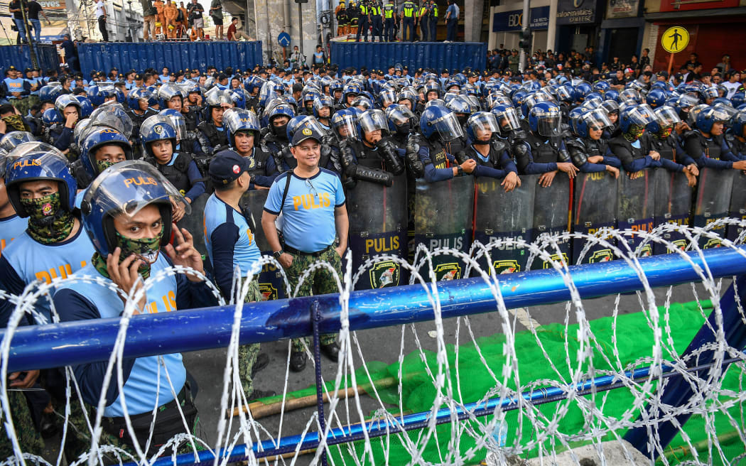 Anti-Riot police stand guard behind barbed wire during an anti-corruption rally near Malacanang Palace in Manila.