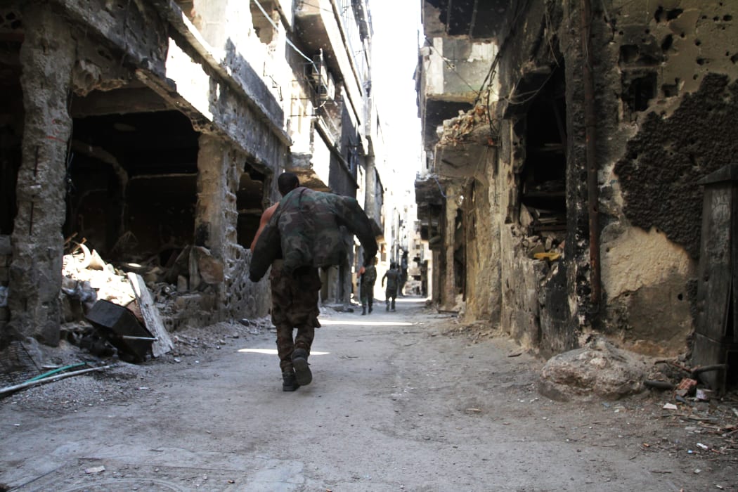 Men walk past destroyed buildings in the Yarmuk Palestinian refugee camp in the Syrian capital Damascus on April 6, 2015.
