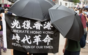 Protesters hold a "Liberate Hong Kong, Revolution of our times" flag while covering their face due to the now introduced National Security Law in Hong Kong, China, on July 1, 2020.