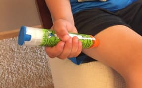 A young boy demonstrates how to use an EpiPen to treat anaphylaxis.