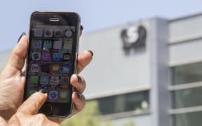 An Israeli woman uses her iPhone in front of the building housing the Israeli NSO group, on August 28, 2016, in Herzliya, near Tel Aviv.