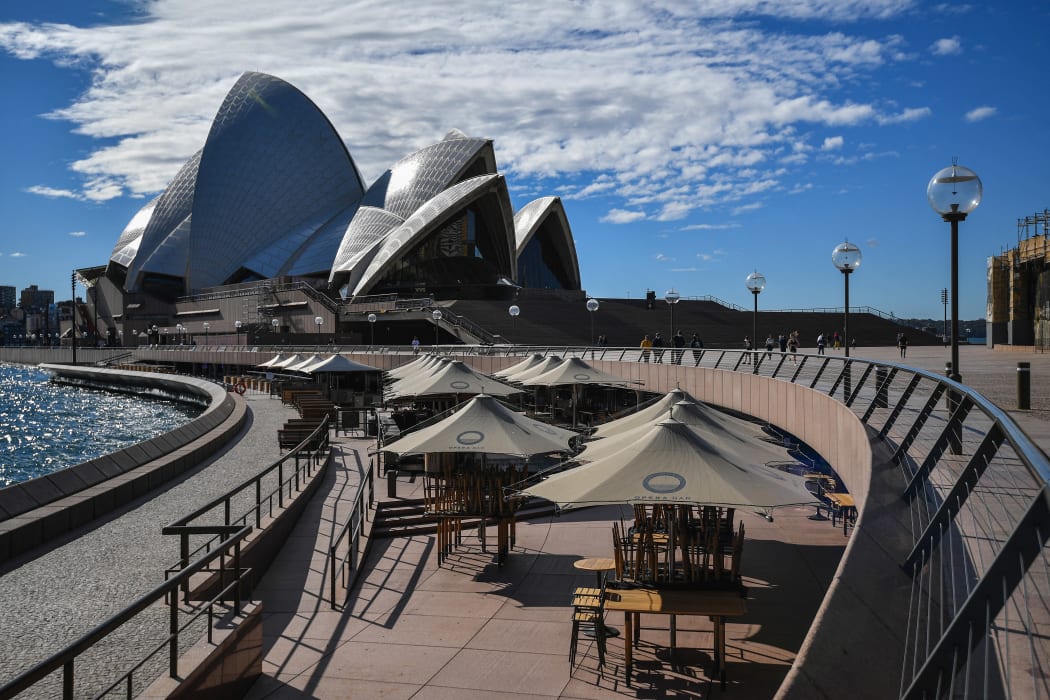 People walk near the Opera House in Sydney on June 26, 2021, after authorities locked down several central areas of Australia's largest city to contain an outbreak of the highly contagious Delta variant.