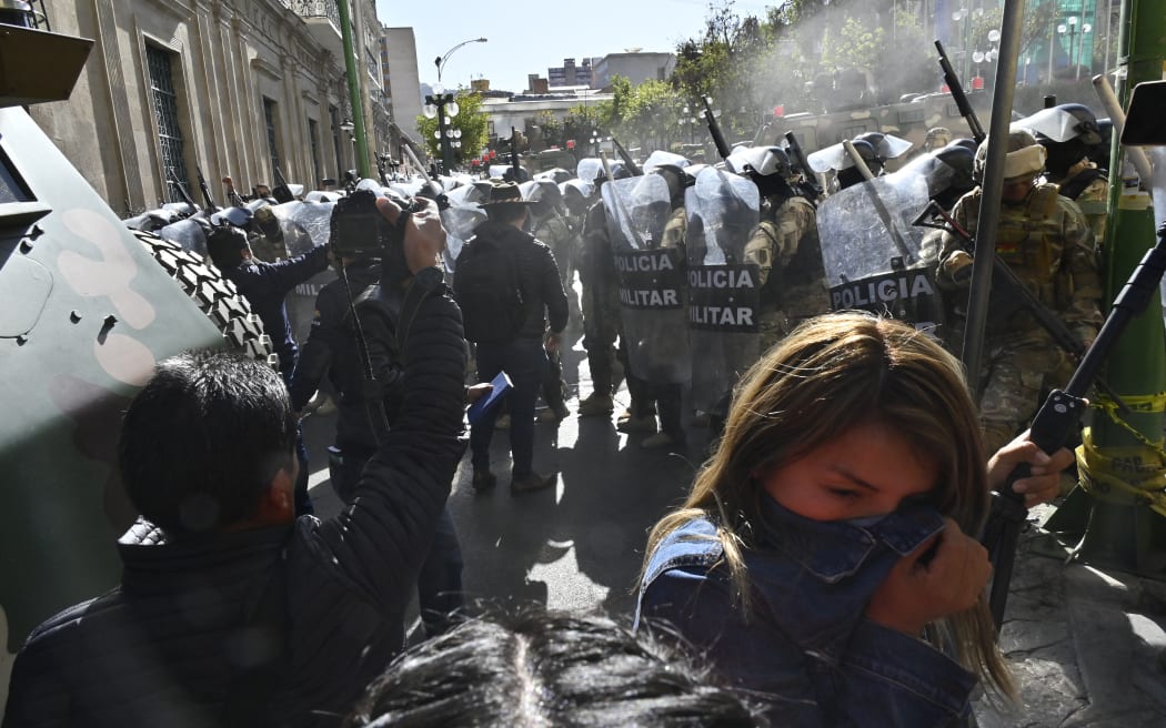 A woman walks away from tear gas fired by military troops outside the Quemado Palace at Plaza Murillo in La Paz on June 26, 2024. Bolivian President Luis Arce on Wednesday denounced the unauthorized gathering of soldiers and tanks outside government buildings in the capital La Paz, saying "democracy must be respected." "We denounce irregular mobilizations by some units of the Bolivian Army," Arce wrote on the X social network. Former president Evo Morales wrote on the same medium that "a coup d'état is brewing." (Photo by AIZAR RALDES / AFP)