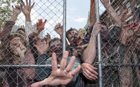 People dressed as zombies push onto a fence at the Universal Studios Hollywood Opening of its New Permanent Daytime Attraction  "The Walking Dead"  in Universal City, California on June 28, 2016. (Photo by VALERIE MACON / AFP)