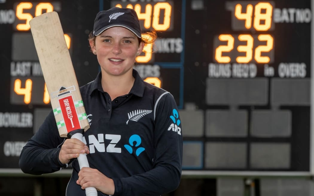 Amelia Kerr in front the scoreboard showing her record score.