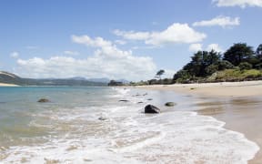 The tide comes in at the beach in Omapere, New Zealand.