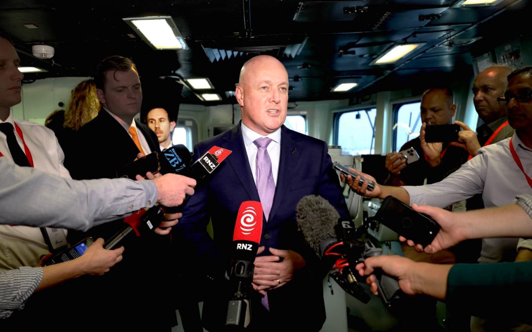 Prime Minister Christopher Luxon speaks to media while deputy press secretary Michael Forbes looks on during a press conference on navy ship HMNZS Te Kaha in India on 20 March 2025.