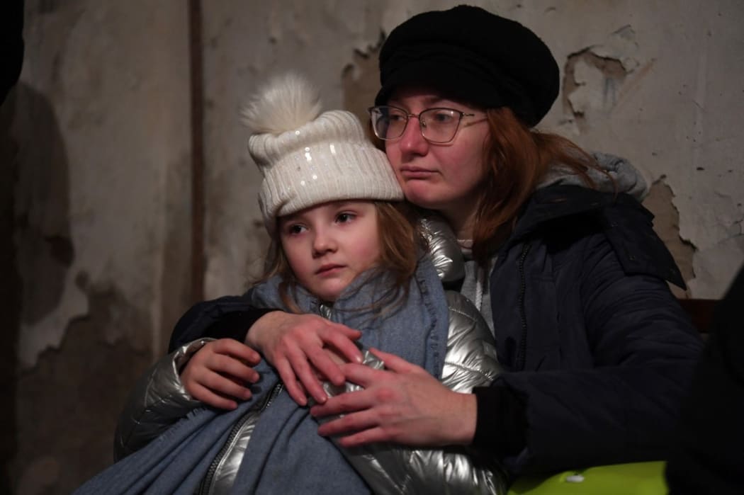 Helga Tarasova hugs her daugther Kira Shapovalova as they wait in a undergound shelter during bombing alert in the Ukrainian capital of Kyiv on February 26, 2022.