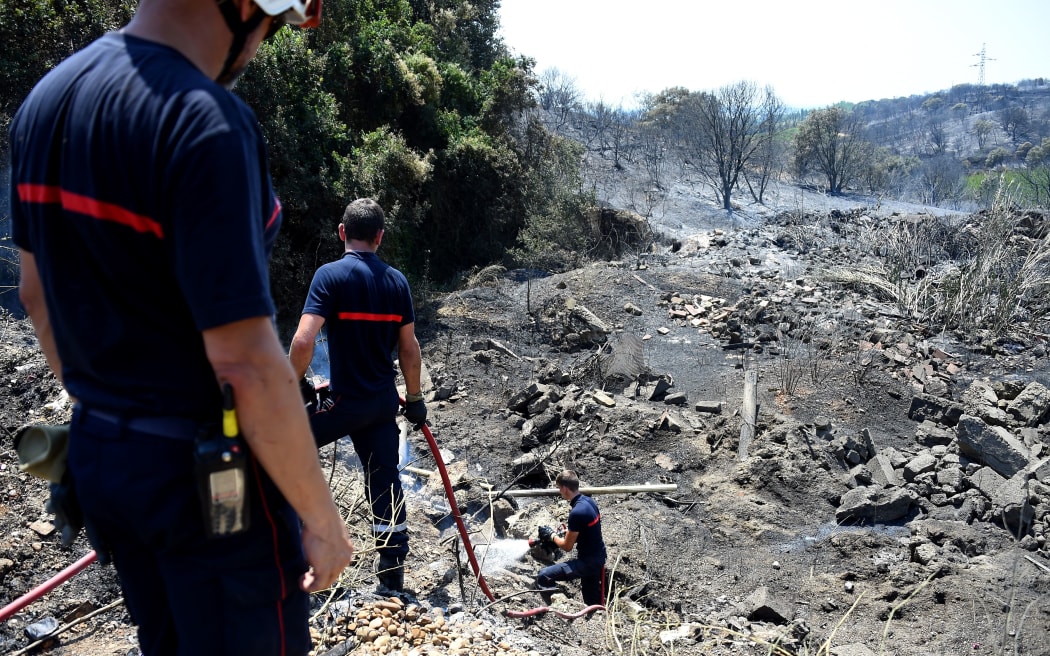 French firefighters extinguish a fire after brushfire hit the countryside around Saint Gilles, on June 29, 2019