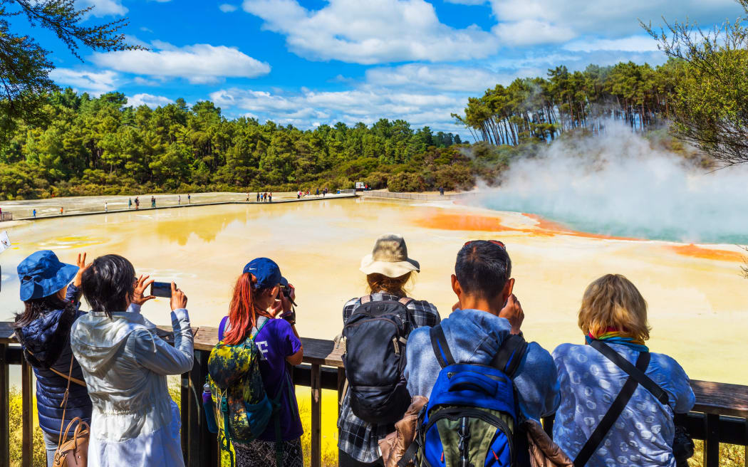 一群人在参观 Wai-O-Tapu 公园的地热池。